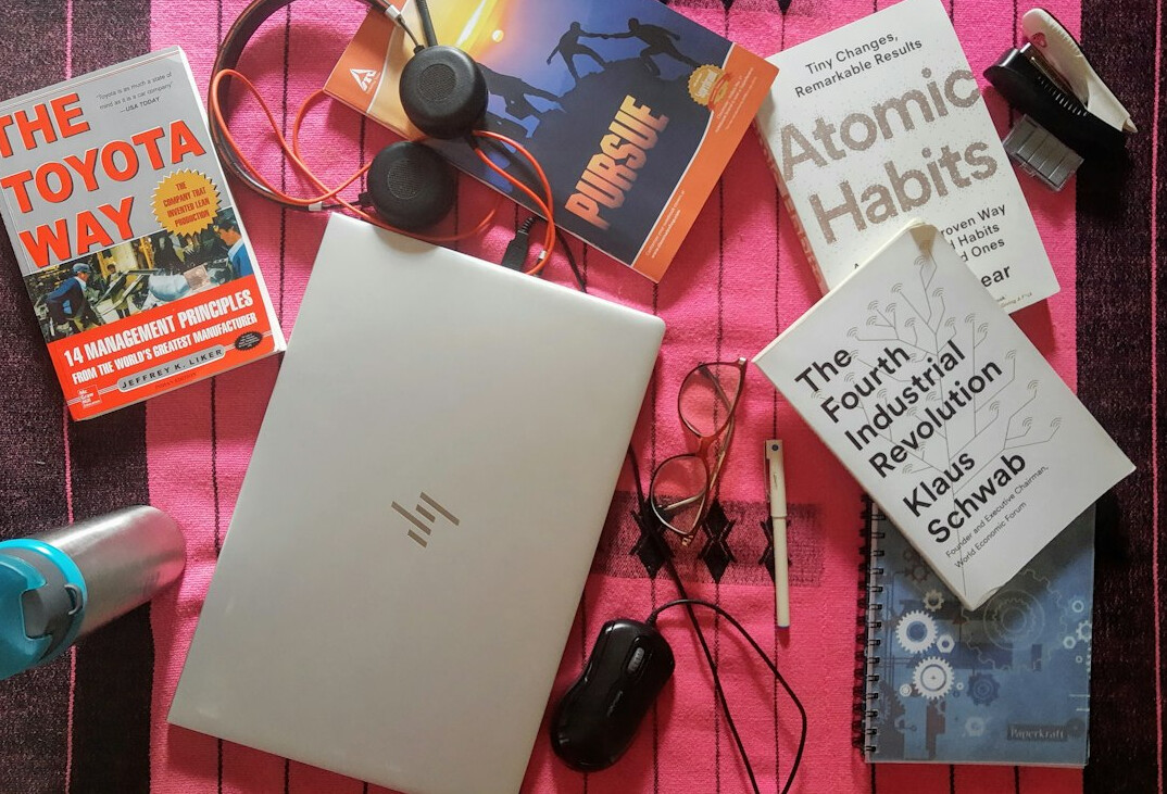 Top-down view of a desk with laptop, notebook and coffee cup